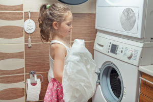 cute little girl doing laundry at home
